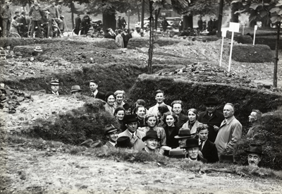 97402 Afbeelding van mensen poserend in een loopgraaf in het plantsoen voor het 3e Administratiegebouw van de ...